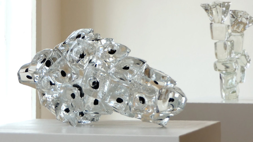 savremena skulptura Toni Kreg od providnog stakla formirana umnožavanjem okruglaste forme sa crnim detaljem u centru